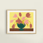 Framed artwork of pink tulips in a green vase on a butter yellow background.